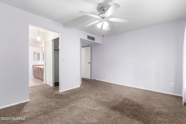 unfurnished bedroom featuring ceiling fan, ensuite bathroom, light carpet, and a closet