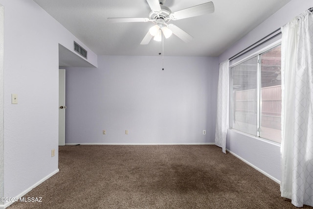 spare room with dark carpet, ceiling fan, and a healthy amount of sunlight