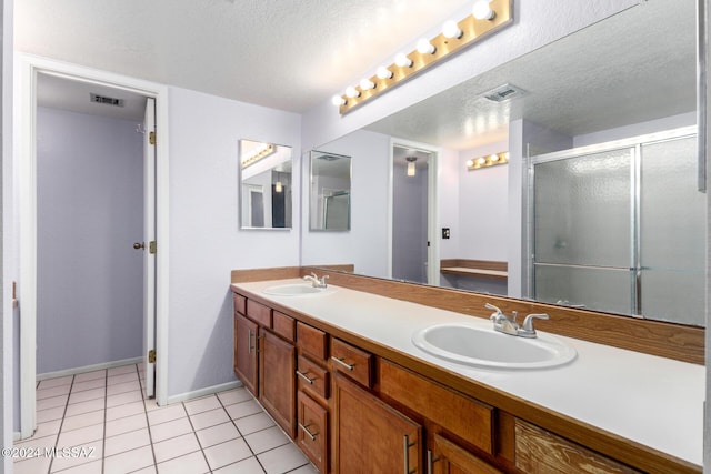 bathroom featuring tile patterned floors, vanity, a shower with shower door, and a textured ceiling