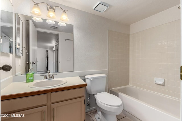 full bathroom with tile patterned flooring, vanity, tiled shower / bath combo, and toilet