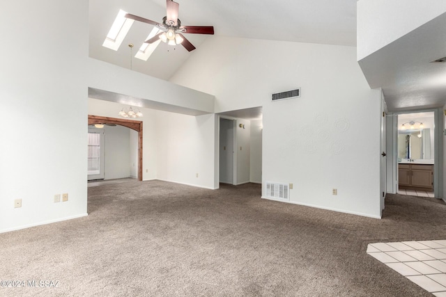 unfurnished living room with a skylight, high vaulted ceiling, ceiling fan, and light colored carpet