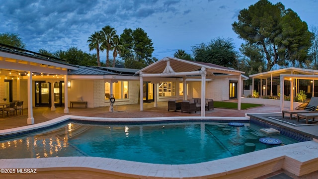 pool at dusk with an outdoor living space, a patio area, and an outdoor structure