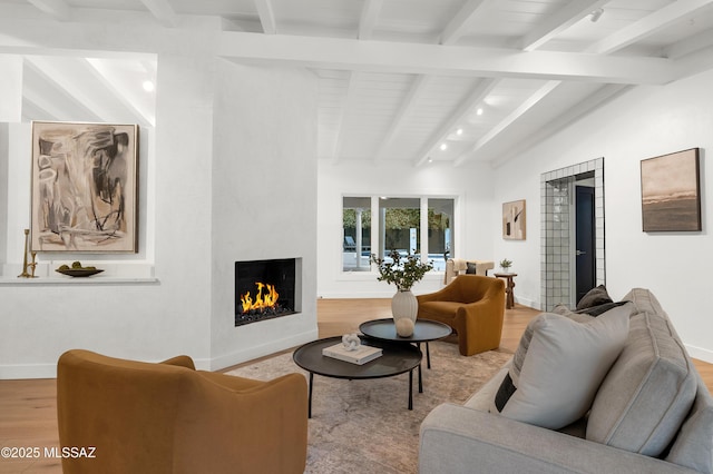 living room with light wood-type flooring, vaulted ceiling with beams, and a large fireplace