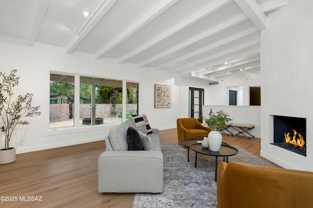 living room with a fireplace, wood-type flooring, beam ceiling, and track lighting