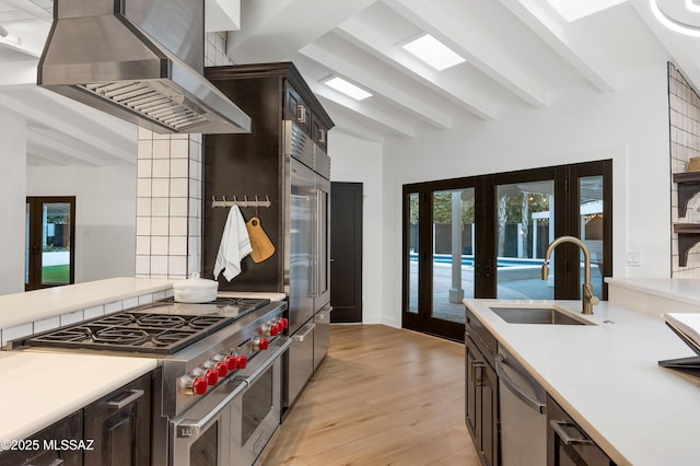 kitchen with beamed ceiling, high end appliances, island exhaust hood, sink, and french doors