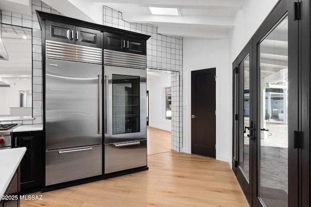 kitchen with beamed ceiling, light hardwood / wood-style floors, and stainless steel built in refrigerator