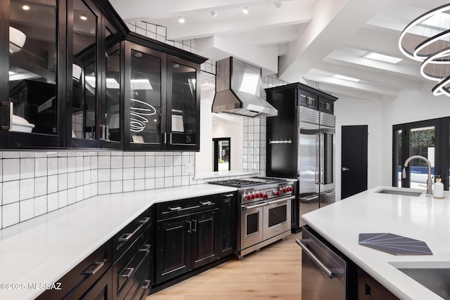 kitchen featuring beam ceiling, range hood, sink, tasteful backsplash, and high end appliances