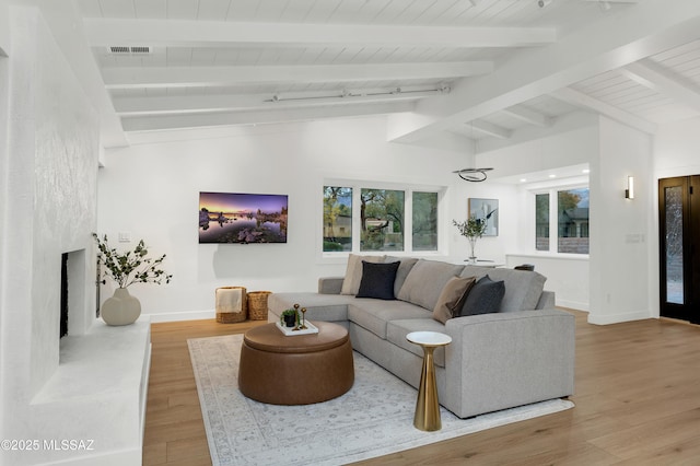 living room with hardwood / wood-style flooring and vaulted ceiling with beams