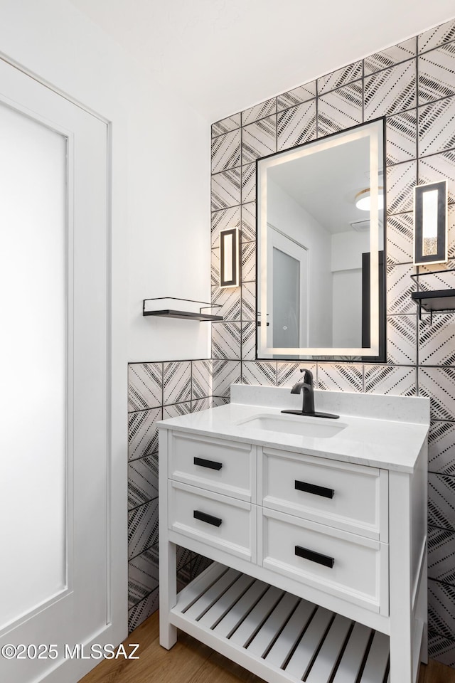 bathroom with tile walls, backsplash, vanity, and hardwood / wood-style flooring