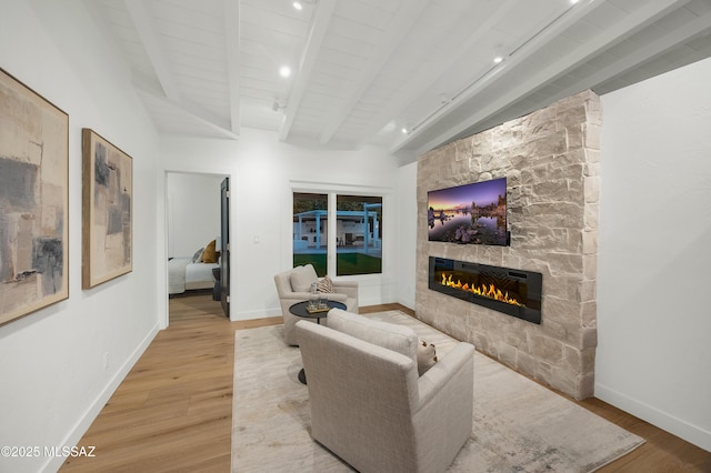 living room featuring light hardwood / wood-style floors, beam ceiling, wood ceiling, and a fireplace