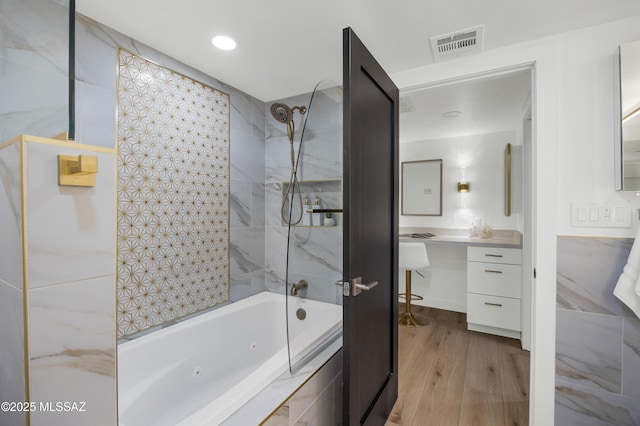 bathroom featuring hardwood / wood-style floors, tiled shower / bath, and vanity