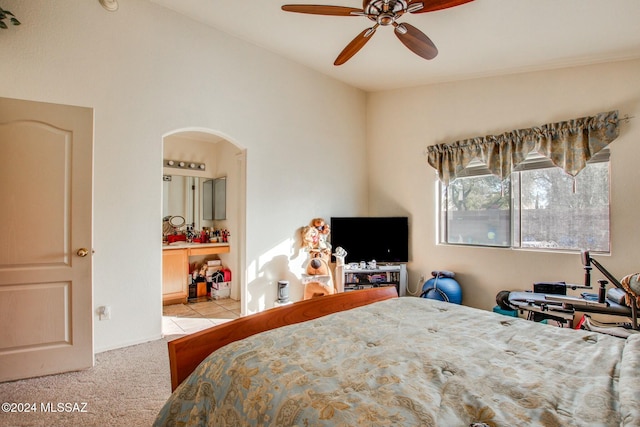 bedroom with vaulted ceiling, light colored carpet, ensuite bath, and ceiling fan