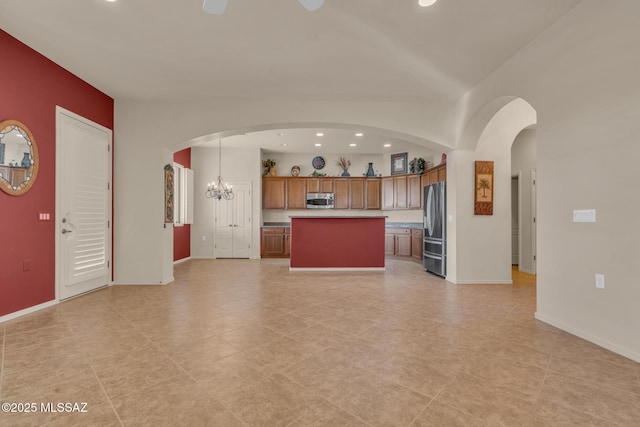 kitchen featuring pendant lighting, a center island, stainless steel appliances, and an inviting chandelier