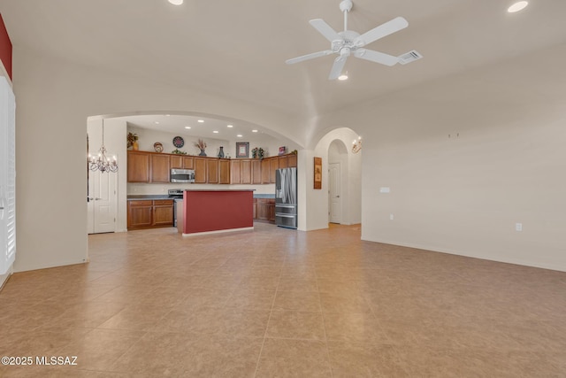 kitchen featuring light tile patterned flooring, ceiling fan with notable chandelier, appliances with stainless steel finishes, decorative light fixtures, and a kitchen island