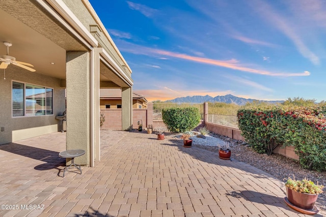 patio terrace at dusk with ceiling fan and a mountain view