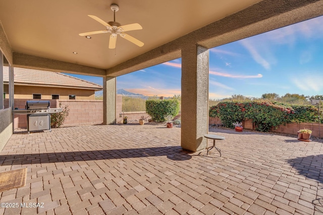 patio terrace at dusk featuring ceiling fan and grilling area