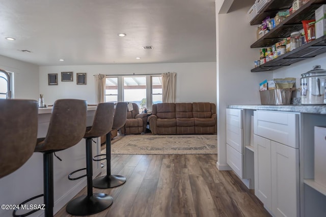 living room with wood finished floors, visible vents, and recessed lighting