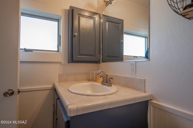 bathroom with a decorative wall, vanity, and wainscoting