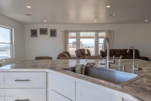 kitchen with recessed lighting, visible vents, open floor plan, white cabinetry, and a sink