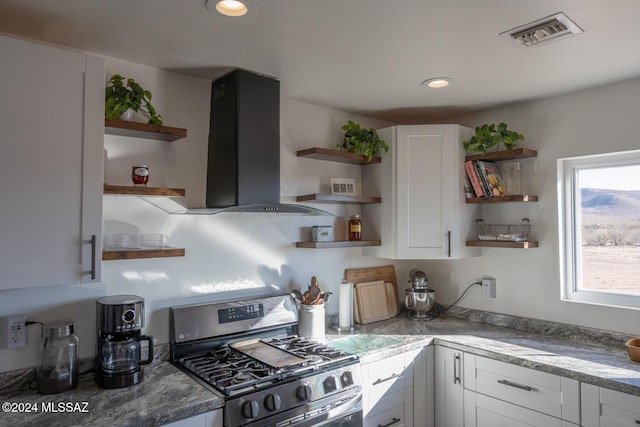 kitchen featuring open shelves, island exhaust hood, stainless steel range with gas stovetop, and white cabinets