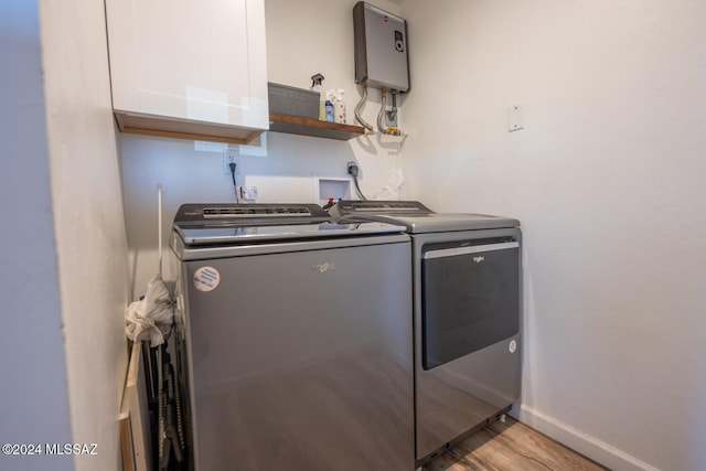 laundry area with cabinet space, baseboards, washer and dryer, light wood-style floors, and water heater