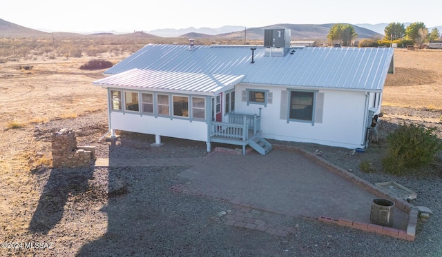 view of front of house with central air condition unit, a sunroom, a mountain view, and metal roof