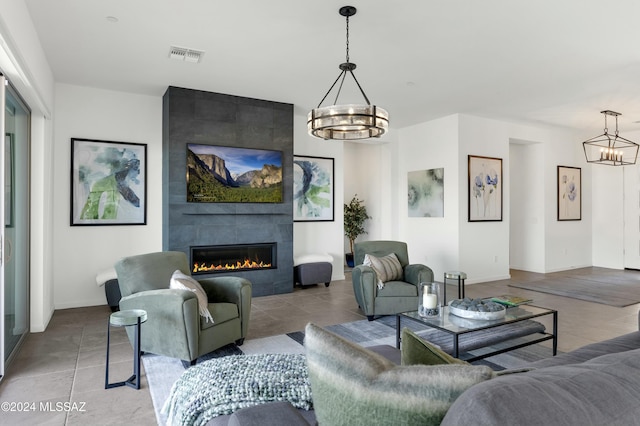 living room featuring a fireplace, visible vents, baseboards, and a notable chandelier
