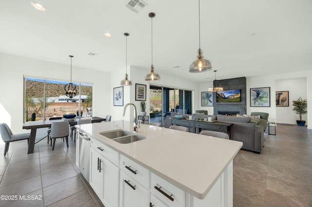 kitchen featuring a sink, dishwasher, a large fireplace, visible vents, and recessed lighting