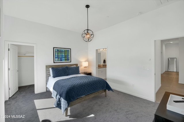 bedroom featuring ensuite bath, baseboards, carpet, and a walk in closet