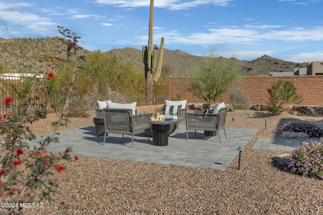 view of patio featuring a fenced backyard, an outdoor living space with a fire pit, and a mountain view