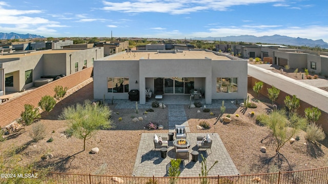 rear view of property featuring a fire pit, a mountain view, and a patio area