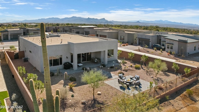 exterior space with a patio, a fenced backyard, a mountain view, and stucco siding
