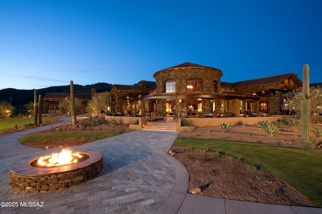 view of front of house featuring a mountain view and an outdoor fire pit