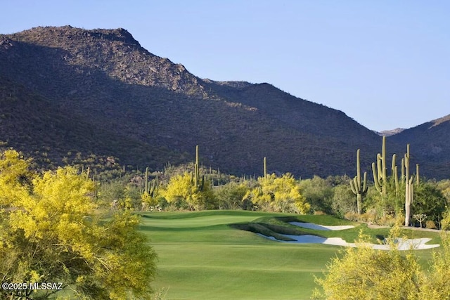 surrounding community featuring a lawn, a mountain view, and view of golf course