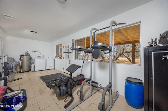 exercise area featuring light tile patterned flooring, independent washer and dryer, and water heater