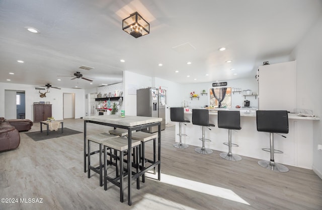 dining space with ceiling fan and light hardwood / wood-style flooring