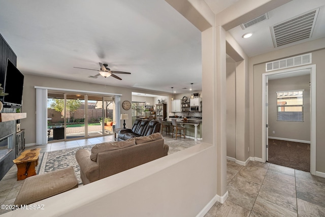 living room featuring ceiling fan and a fireplace