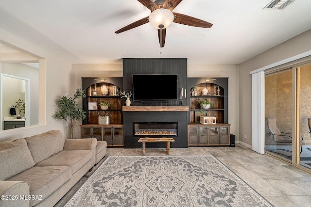 living room with built in shelves, ceiling fan, and a fireplace