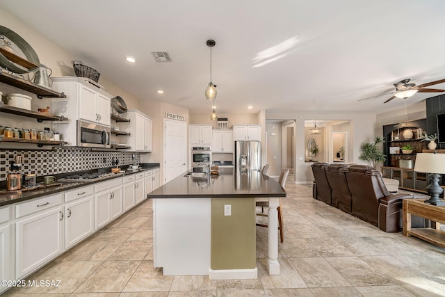 kitchen with white cabinetry, ceiling fan, stainless steel appliances, an island with sink, and pendant lighting