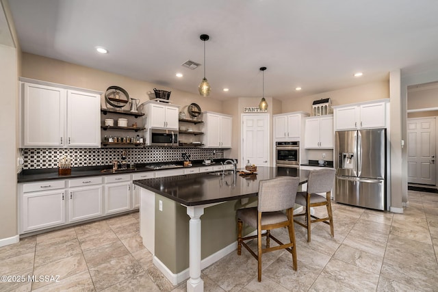 kitchen featuring appliances with stainless steel finishes, a center island with sink, white cabinetry, and sink