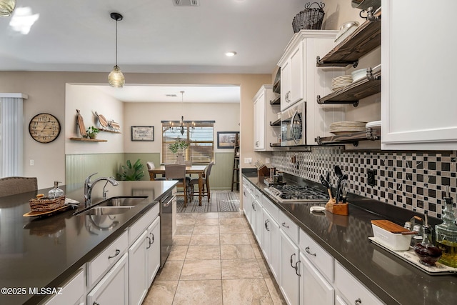 kitchen featuring decorative backsplash, appliances with stainless steel finishes, sink, white cabinets, and hanging light fixtures