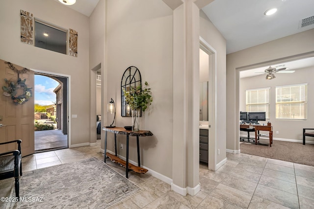 foyer featuring ceiling fan and light colored carpet