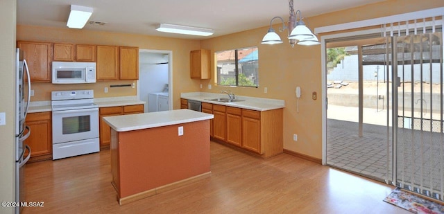 kitchen with sink, stainless steel appliances, a center island, separate washer and dryer, and decorative light fixtures