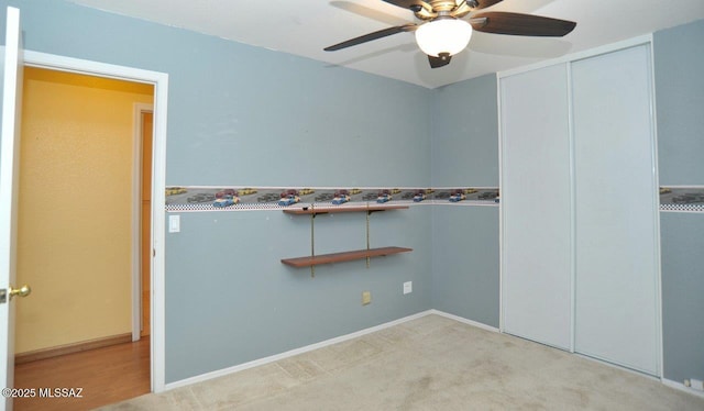 unfurnished bedroom with ceiling fan, light colored carpet, a walk in closet, and a closet