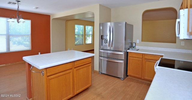 kitchen featuring a kitchen island, decorative light fixtures, stainless steel fridge, a chandelier, and light hardwood / wood-style flooring