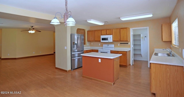 kitchen featuring white appliances, sink, decorative light fixtures, light hardwood / wood-style flooring, and a center island