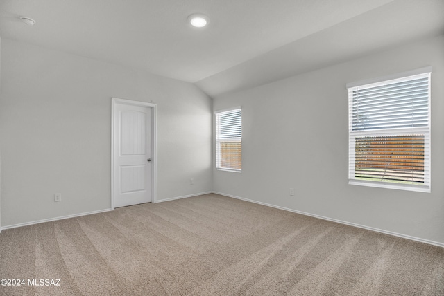 carpeted spare room featuring lofted ceiling