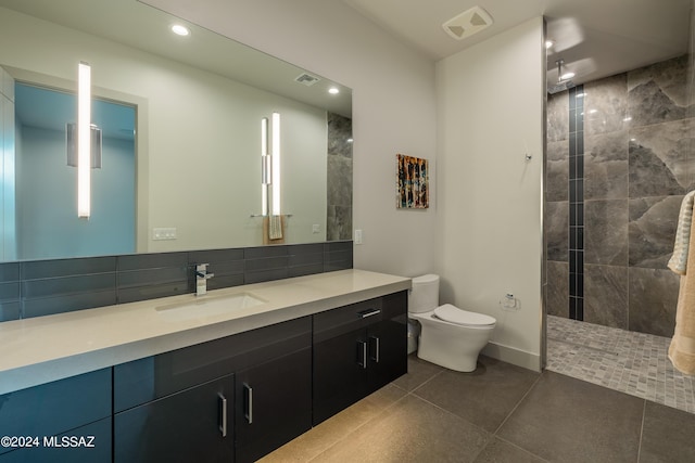 bathroom with tile patterned floors, toilet, vanity, and a tile shower