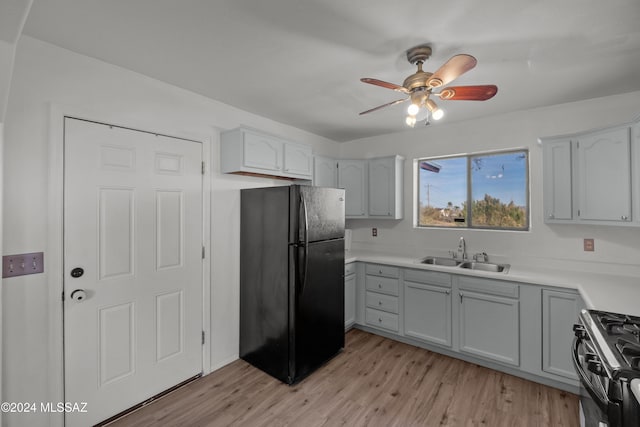 kitchen with ceiling fan, stainless steel range, sink, black fridge, and light hardwood / wood-style flooring