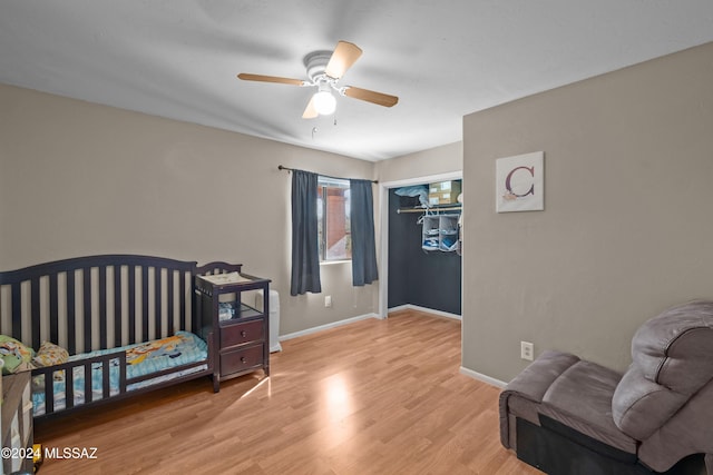 bedroom with ceiling fan, a closet, light hardwood / wood-style flooring, and a nursery area